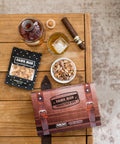 Damn, Man Snacks Snack Pack Box on table with cigar and whiskey in glass