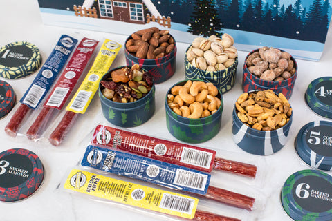 "Assortment of savory meat sticks and gourmet nuts in tins for the 12 Days of Winter Wonder gift set"